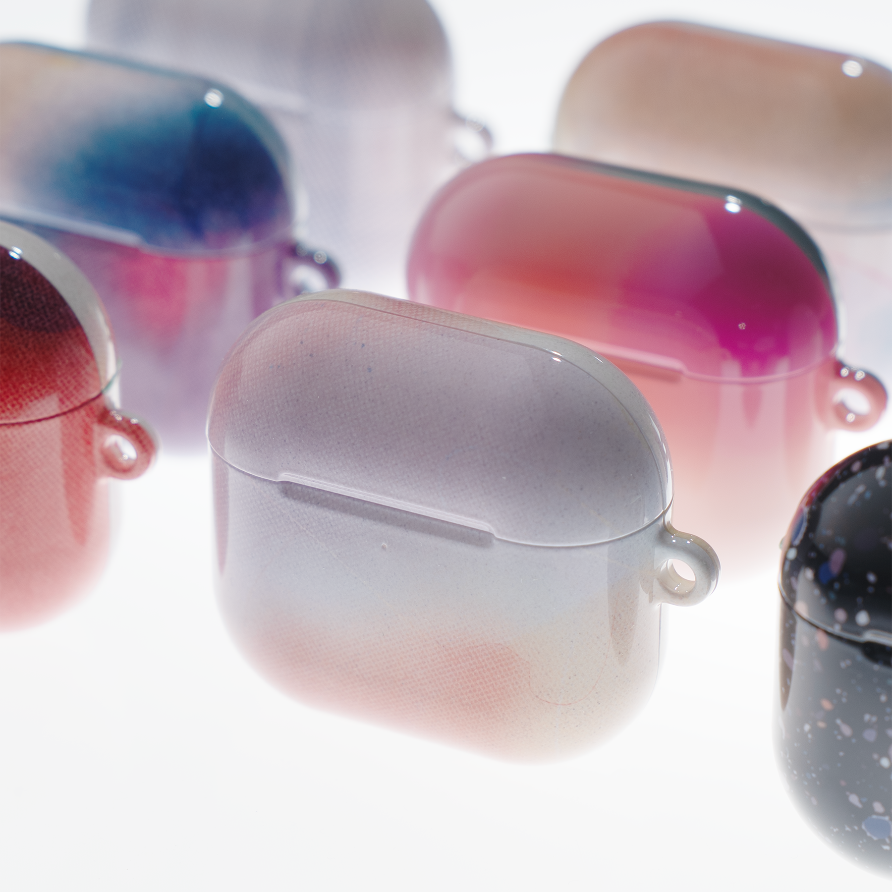 Gradient-colored AirPods cases on a white background
