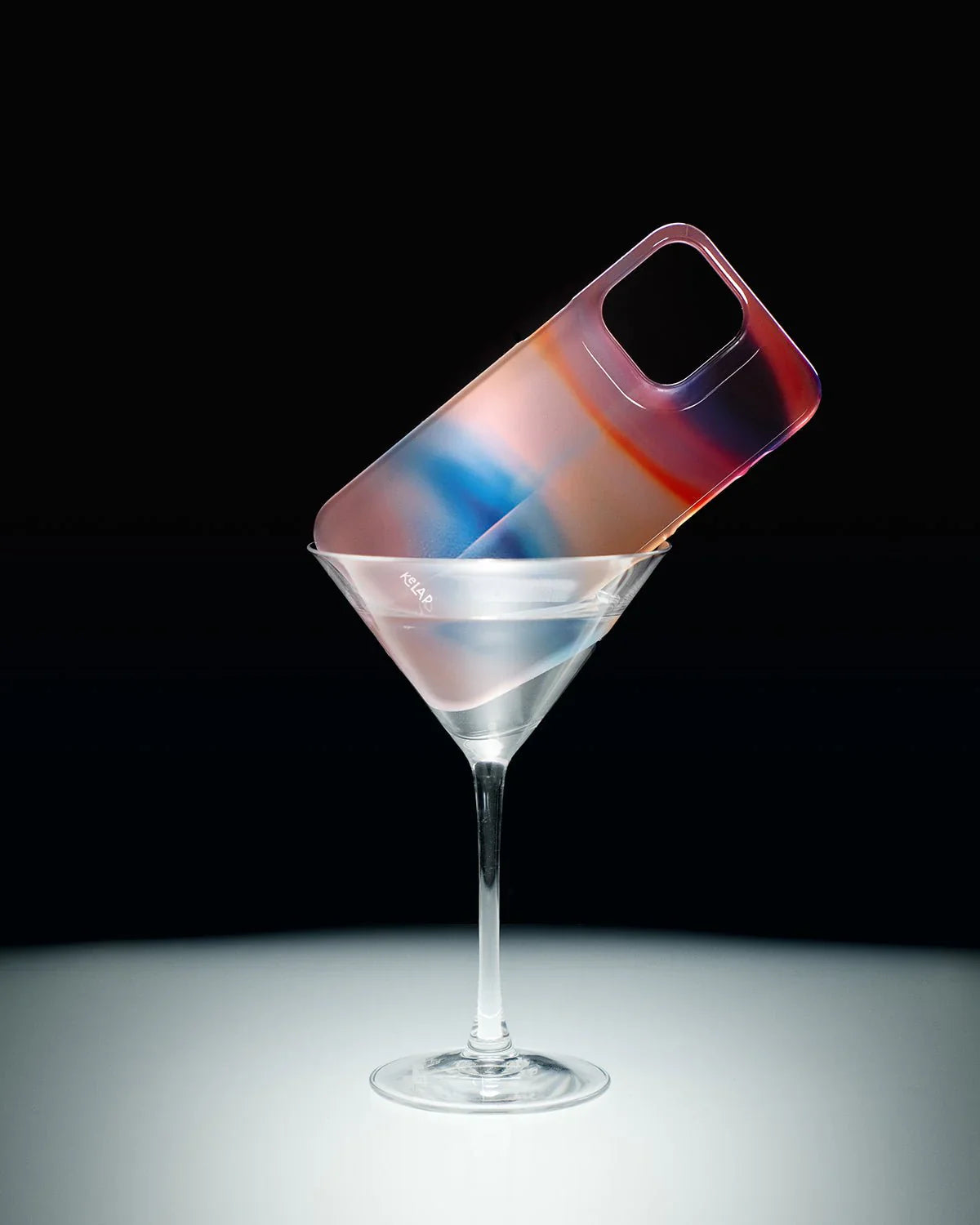 Stylized display of KELAB's pastel-toned iPhone case in a martini glass, highlighting its artistic and aesthetic appeal.