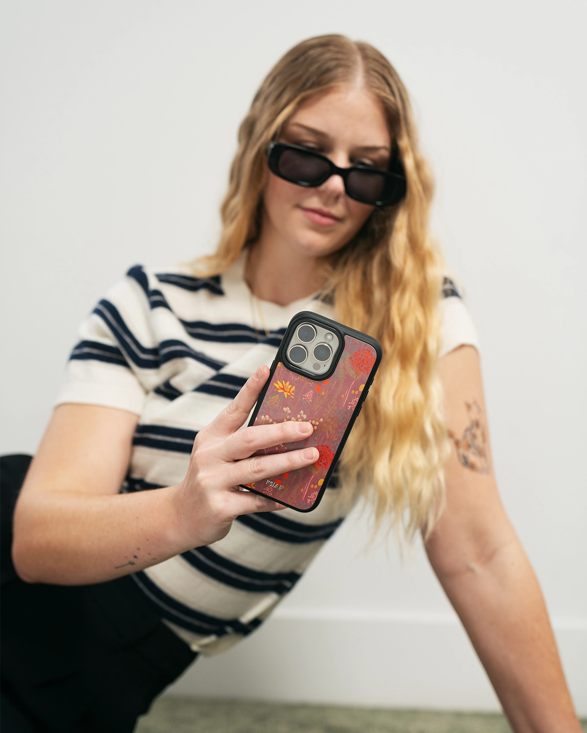 A woman holding a phone with a pink flower case.