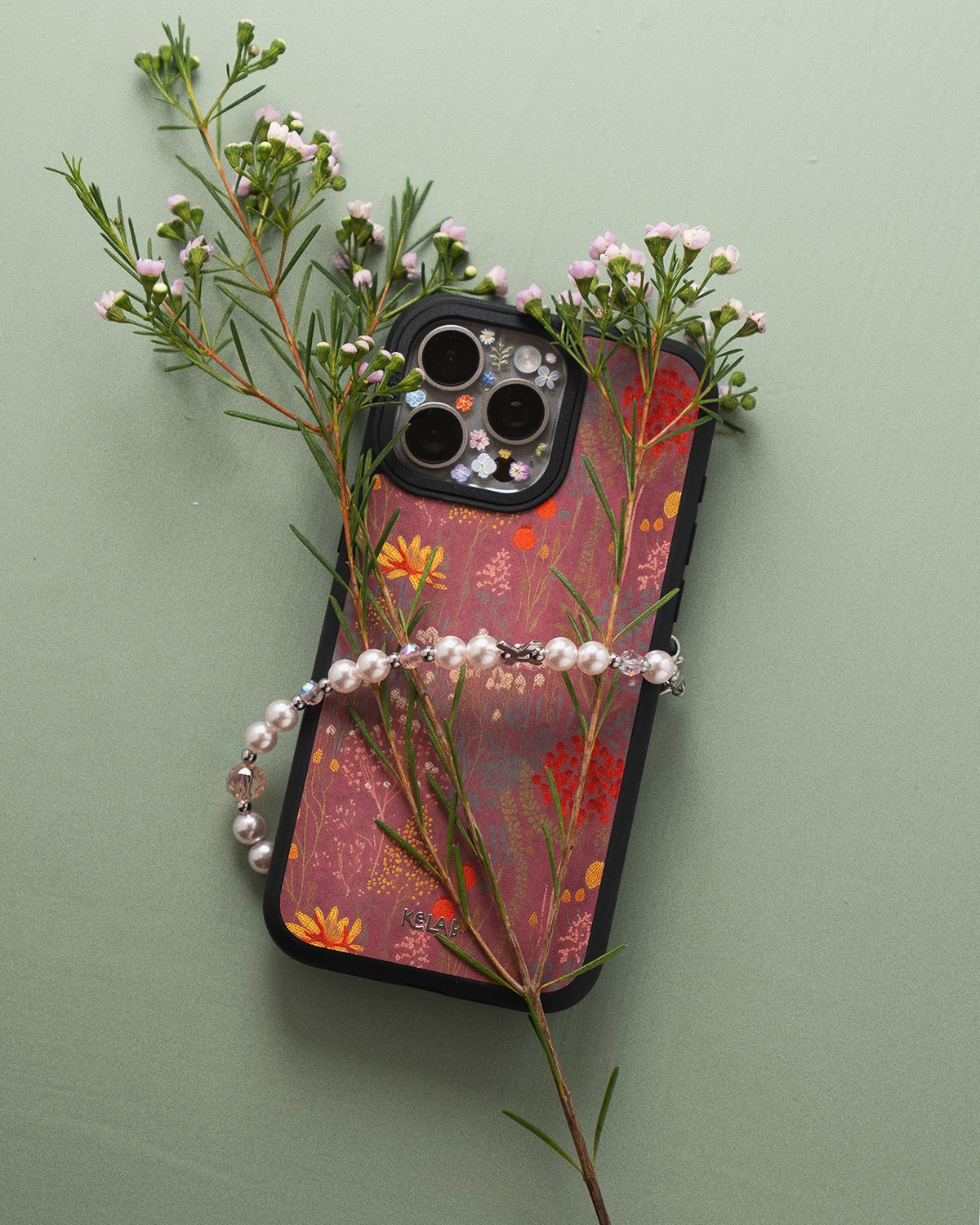 Phone case with floral design and greenery on a light green background