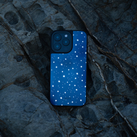 Starry Blue iPhone Reflective Mirror Case by KELAB featuring a deep blue gradient with reflective stars, placed on textured rock surface. Ideal for stargazers and style lovers.